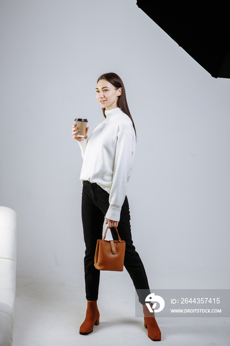 girl with bag and coffee posing on a light background