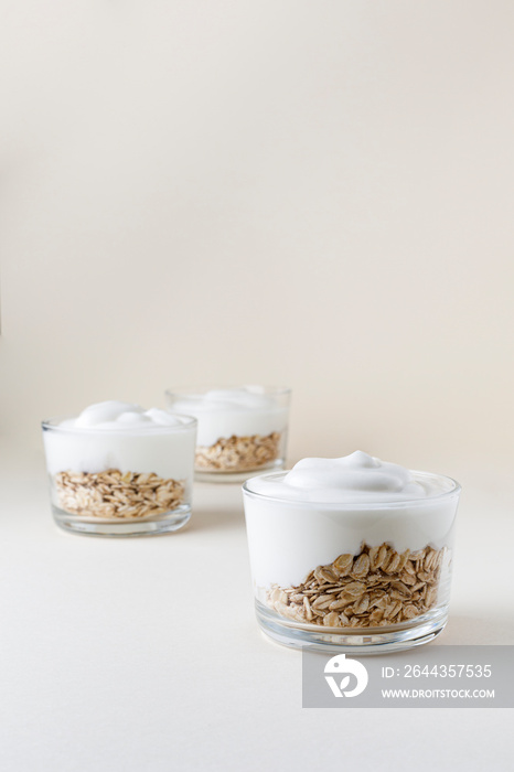 Creamy yogurt with oat flakes with beige background