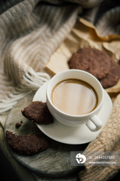 Cup of coffe with milk and chocolate cookies on warm wool blanket