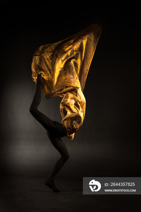 ballerina with golden fabric on a black background