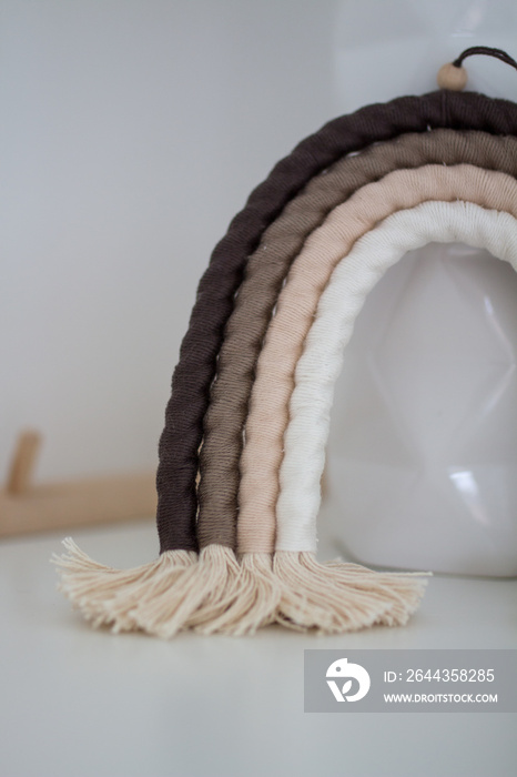 Macrame rainbow with white cotton braided rope and colorful wools on white background.