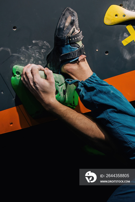 A young, athletic guy with a beautiful inflated body climbs a bouldering in a climbing hall. Emotions on the face.