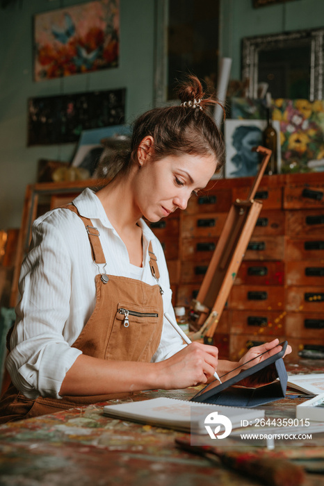 Portrait of young woman artist drawing on the digital tablet