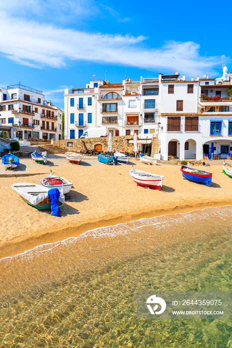 Fishing boats on beach in Port Bo with colorful houses of old town of Calella de Palafrugell in background, Catalonia, Spain