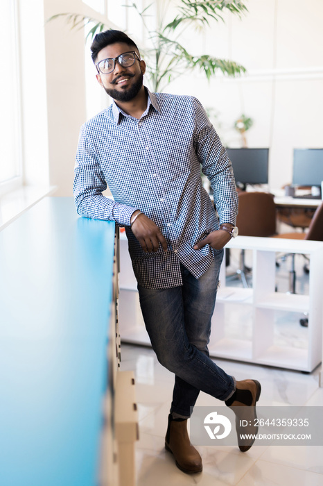 Happy indian business man standing in modern office