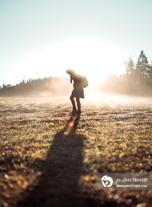 Girl standing in thick fog with a colorful morning sunlight. Human silhouette in different poses in autumn.