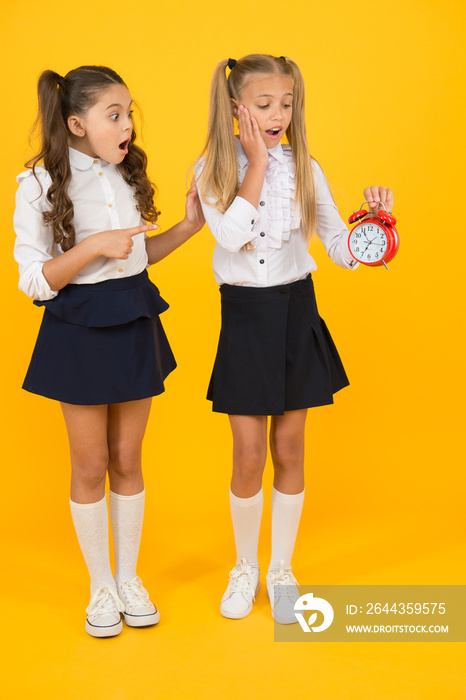 Time for break and relax. Alarm ringing. Time for lunch. School schedule. Schoolgirls and alarm clock. Children school pupils adorable formal uniform outfit. Kids hold alarm clock counting time