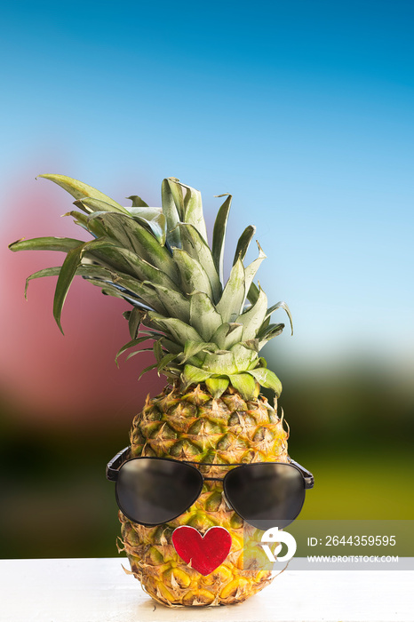 fresh pineapple fruit wearing sunglasses on wooden