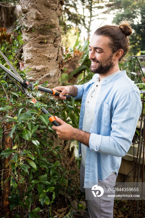 Happy worker using hedge clippers at garden