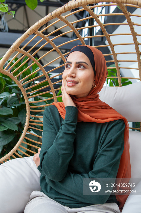 Portrait of woman wearing headscarf sitting in swing chair