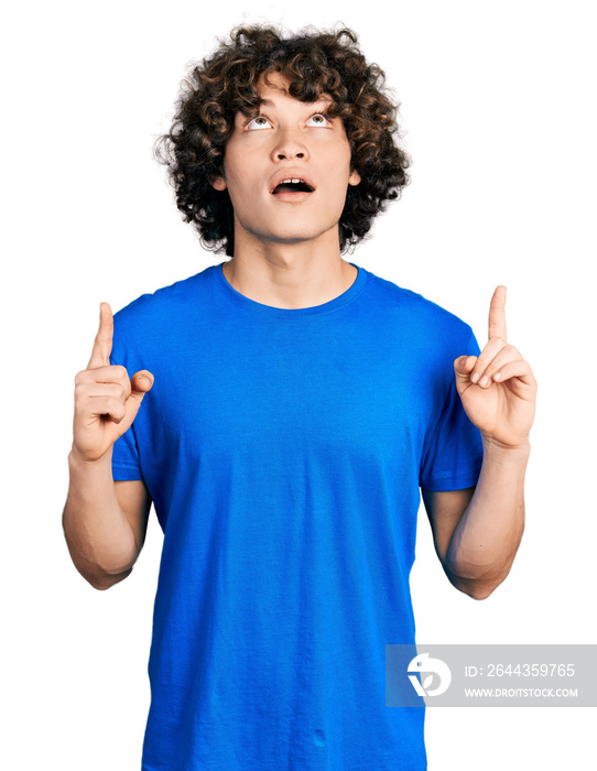 Caucasian teenager wearing casual clothes amazed and surprised looking up and pointing with fingers and raised arms.