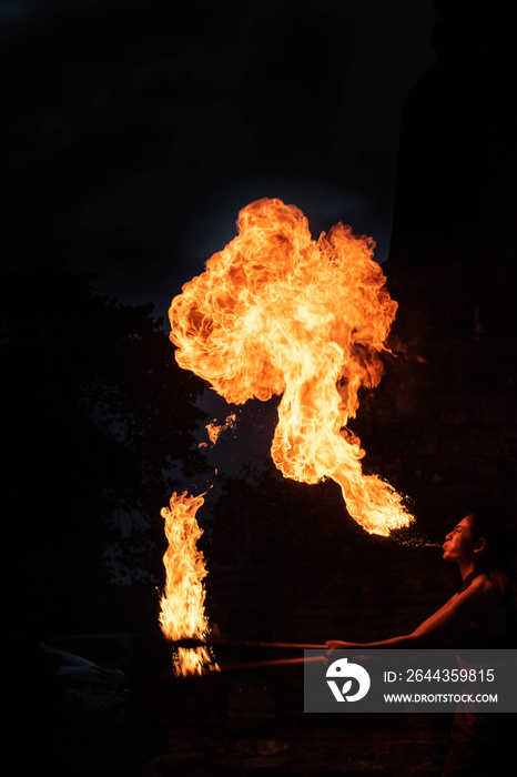 a fire artist blowing a large flame from her mouth ( a woman spits fire) in Thailand