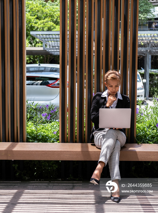 Business woman working on laptop outdoors stock photo