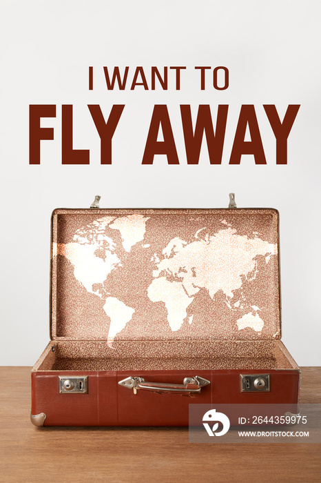 Open vintage suitcase with map and  I want to fly away  lettering