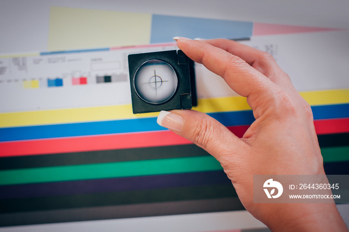 Worker in printing and press centar uses a magnifying glass