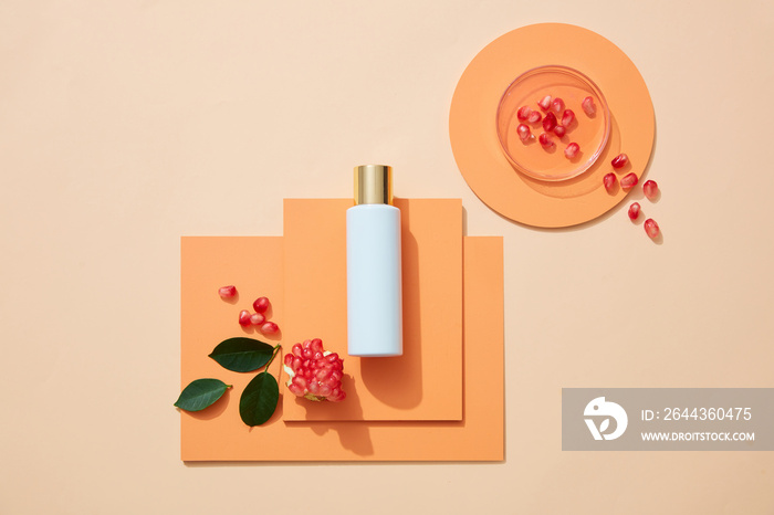 Composition with blank bottle of cosmetic product and pomegranate. Petri dish with pomegranate extract on color background. Flat lay