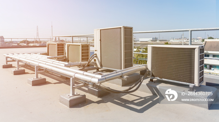 Air compressor machine part of air conditioner system on roof deck with sky background.