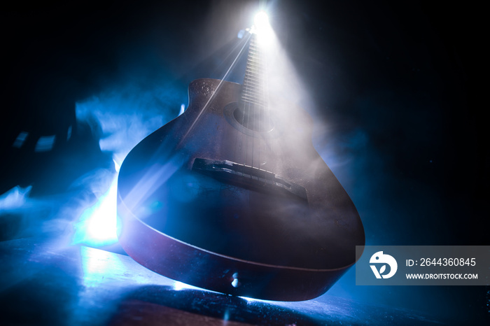 Music concept. Acoustic guitar isolated on a dark background under beam of light with smoke with copy space. Guitar Strings, close up. Selective focus. Fire effects. Surreal guitar