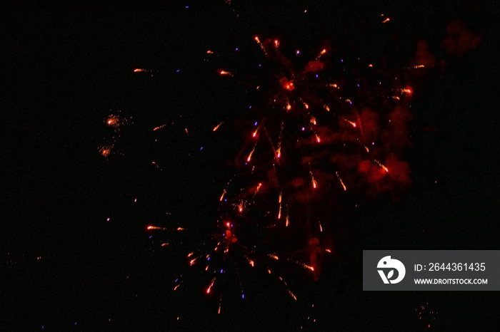 Festive fireworks, red sparks, with a slight haze, against the background of the night sky