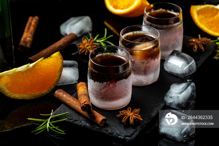 frozen herb liqueur in small glass. Shot glass of herb liqueur with cinnamon and oranges on a dark background