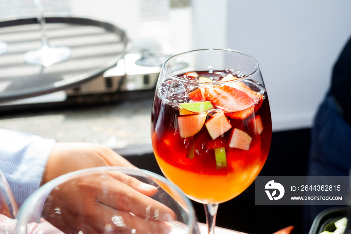 Drink prepared with wine and orange juice accompanied with ice and fresh fruits, festive event in restaurant area, latin man preparing drink.