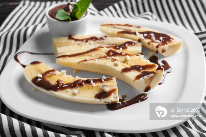 Plate with delicious sliced bananas and chocolate sauce on table