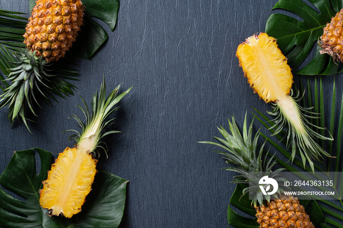 Fresh cut pineapple with tropical leaves on dark blue background.