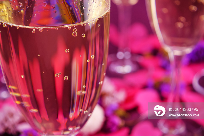 Wine glasses with sparkling wine on a lilac background and golden confetti.