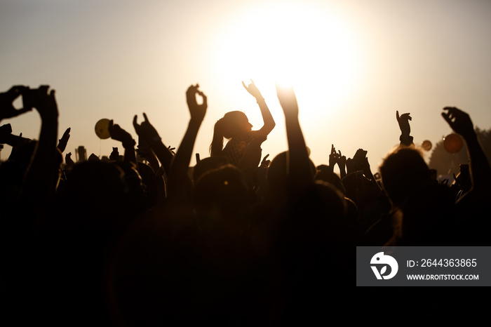 The crowd enjoys the summer music festival, sunset, the silhouettes hands up