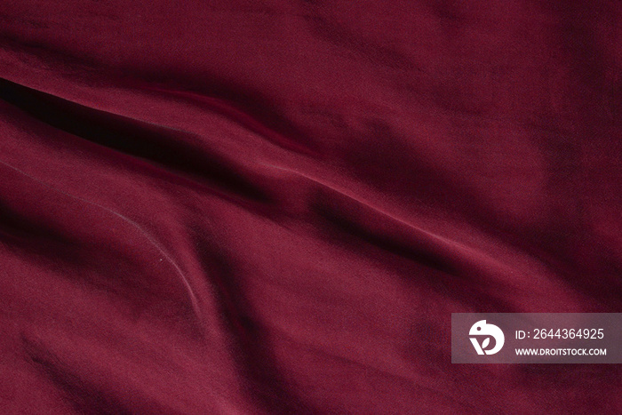 Soft smooth burgundy silk fabric background. Fabric texture.