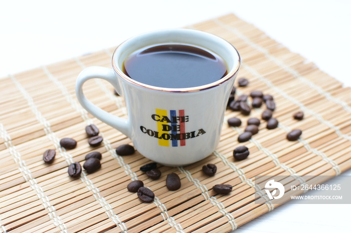 Traditional cup of Colombian coffee with coffee beans on wooden background