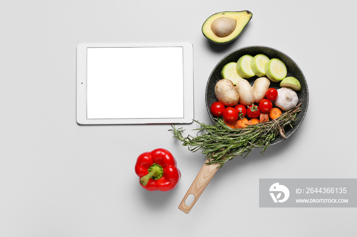 Digital recipe book and frying pan with ingredients on white background