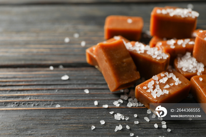 Salted caramel candies on wooden background, space for text