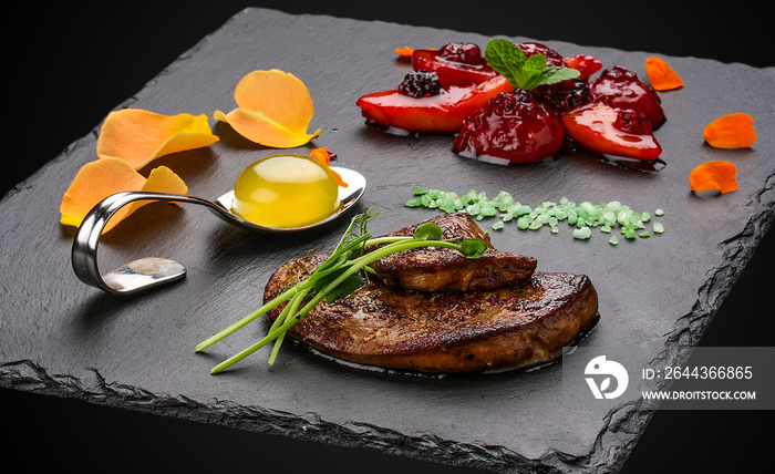 Foie Gras with berries flambe on a dark background