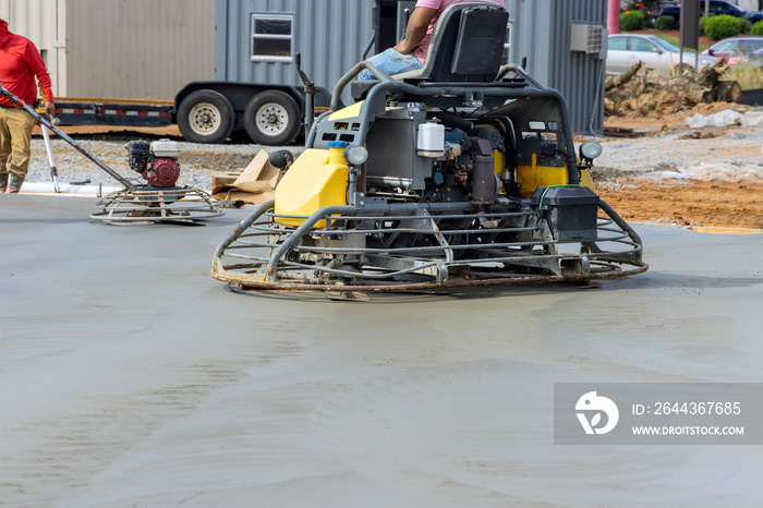 After pouring concrete on the foundation floor, workers are polishing the concrete with concrete polishing machines in construction site