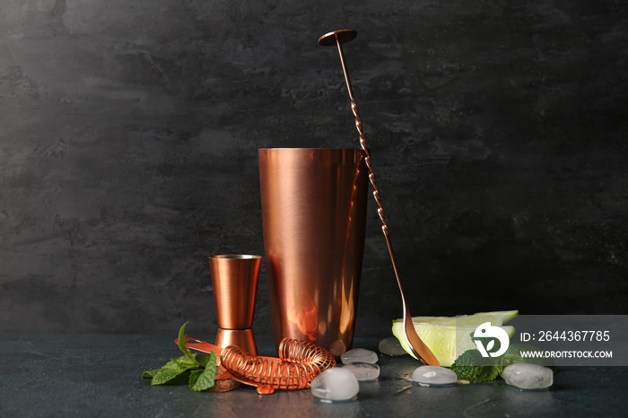 Set of copper cocktail utensils and ingredients on dark background