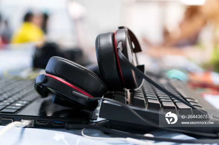 Black Headphones on computer laptop at office desk or working place with meeting room background