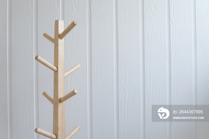 Wooden cloth hanger rack with white wall background copy space.