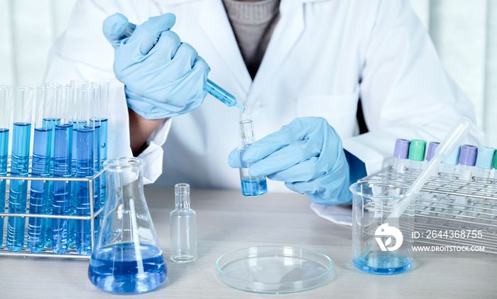 Doctors use a syringe to absorb vaccines, blue chemical liquid for research and analysis in a laboratory, to try and treat bacterial viruses