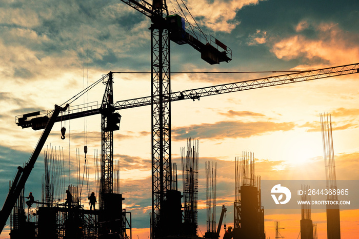 Silhouette of crane construction building towers at sunset