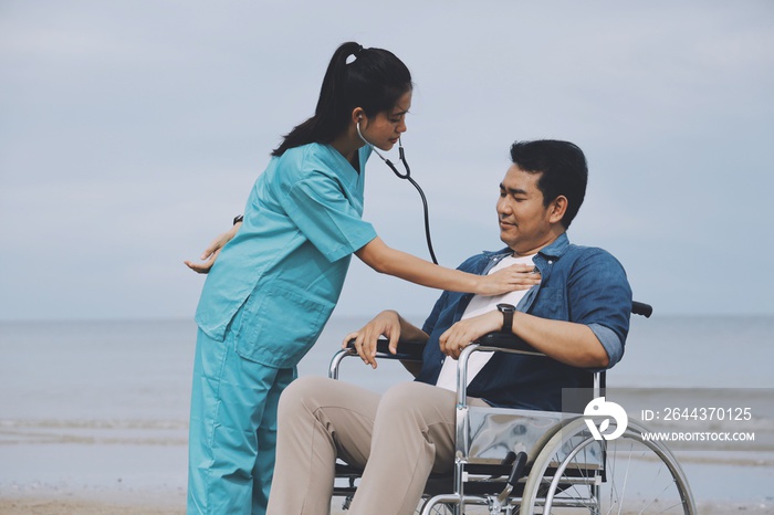 Young Asian man sitting in wheelchair ,Nurse and young man on the beach