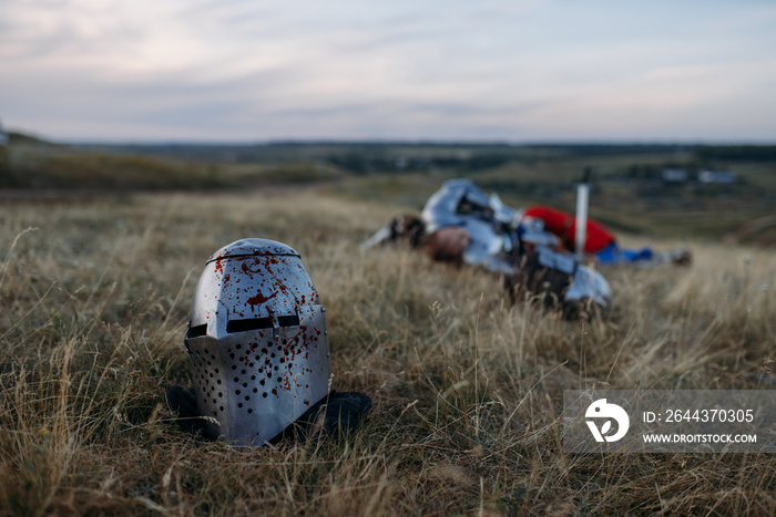 Helmet in blood, dead knight on background