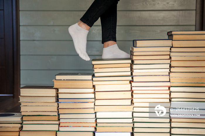 Woman legs on white socks going up to books stairs