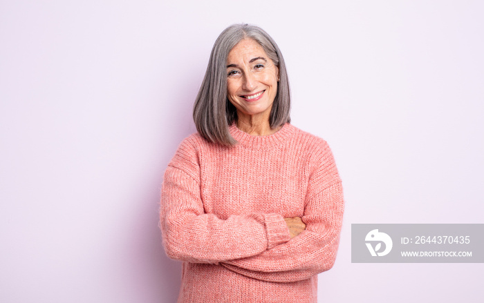 senior pretty woman looking like a happy, proud and satisfied achiever smiling with arms crossed