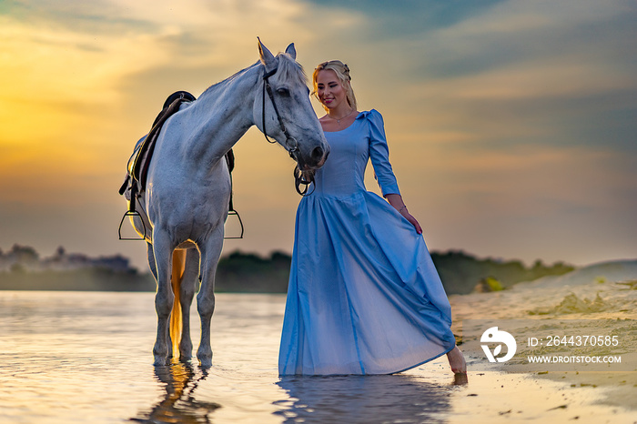 blonde with a horse near the water at sunset