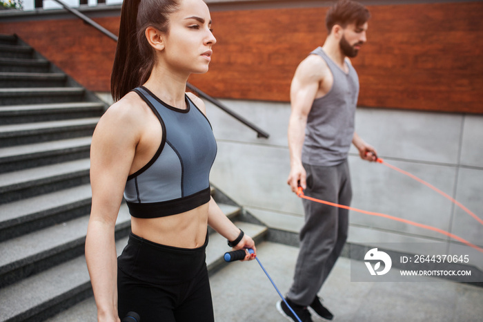 Two strong people are jumping using a rope for that. Guy is jumping more intensive that girl does. He is looking down while she is looking straight forward.