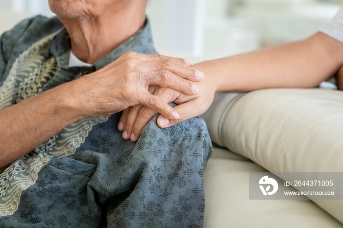 Elderly man holding hand with his son at home