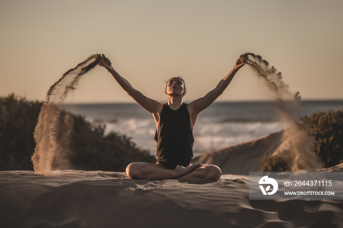 Woman on seashore in asana with flying sand