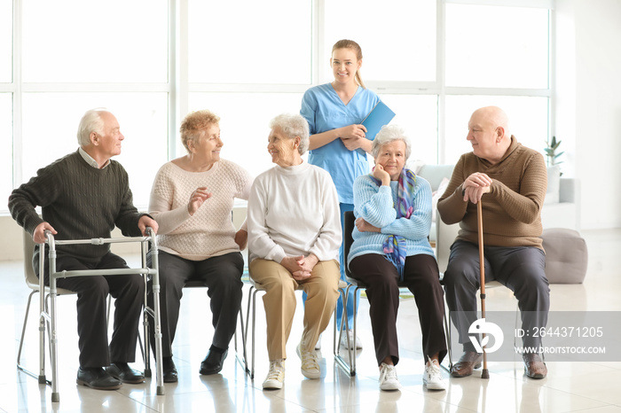 Young caregiver with group of senior people in nursing home