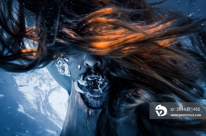 Artistic pic out of focus underwater with long hair man swimming with bubble in water, dark underwater atmosphere with nightmare human abyssal creature like mermaid with beard